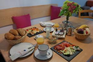 a wooden table with breakfast foods and drinks on it at All Suite Hotel Garni Leithner in Pertisau