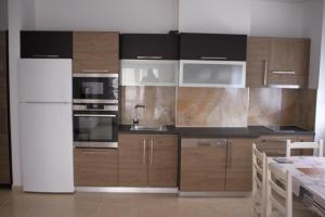 una cocina con armarios de madera y electrodomésticos de acero inoxidable en Everest Apartments Shengjin, en Shëngjin
