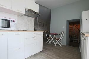 uma cozinha com armários brancos e uma mesa com cadeiras em Elma Stay Location LAlbatros em Saint-Pierre-dʼOléron