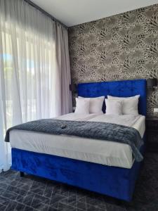 a bedroom with a blue bed with white pillows at Aparthotel PARADISE Dziwnówek in Dziwnówek