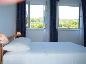 a bedroom with a white bed and two windows at Apartment Villa Green Court in Korčula