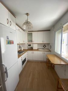 Una cocina con gabinetes blancos y una mesa de madera. en Apartamento Artesanos Ronda, en Ronda