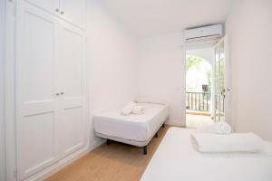 ein weißes Zimmer mit einem Bett und einem Fenster in der Unterkunft Siesta Mar Private Apartments in Cala en Porter