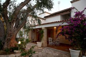 ein Haus mit einem Baum und einer Terrasse mit lila Blumen in der Unterkunft Dimora La Cucchiara - POOL - GARDEN - PARKING in Porto Selvaggio in Santa Caterina di Nardò