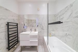 a white bathroom with a sink and a bath tub at Super appartement au cœur de Nice! Bonnes vacances in Nice