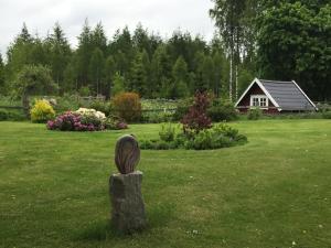 uma estátua num quintal com uma casa ao fundo em Brogård - gårdlejlighed em Agunnaryd