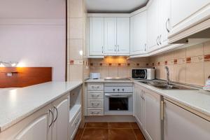 una cucina con mobili bianchi e un lavello di GO2TENERIFE Apart'Elisa Near the beach & Pool view a Playa de las Americas