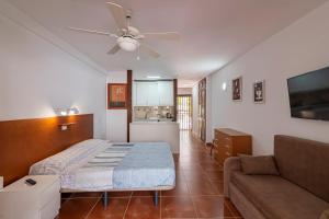 una camera con letto, divano e ventilatore a soffitto di GO2TENERIFE Apart'Elisa Near the beach & Pool view a Playa de las Americas