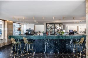a lobby with a bar with three stools at Porto Platanias Beach Resort & Spa in Plataniás
