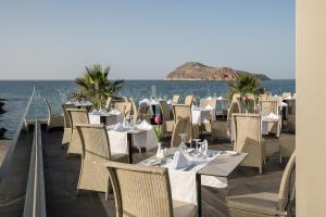 a restaurant with tables and chairs and the ocean at Porto Platanias Beach Resort & Spa in Plataniás