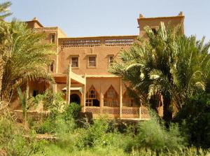 a large house with palm trees in front of it at Kasbah Itrane in Tamnougalt