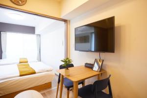 een slaapkamer met een bureau, een bed en een televisie bij SG Premium KASAI in Tokyo