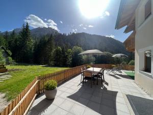 a patio with a table and chairs with mountains in the background at Apartments Oberhollenzer in Braies