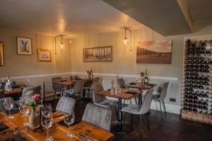 a restaurant with wooden tables and chairs and wine bottles at The George & Dragon Country Inn in Seaton