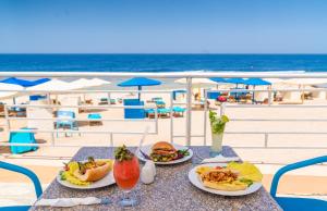 stół z dwoma talerzami jedzenia na plaży w obiekcie Akassia Swiss Resort w mieście Al-Kusajr