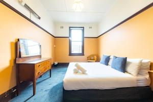 a bedroom with a bed and a dresser and a television at Strathfield Hotel in Sydney