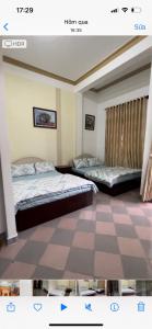 two beds in a room with a checkerboard floor at CSLTDL Quỳnh Nhi in Da Lat