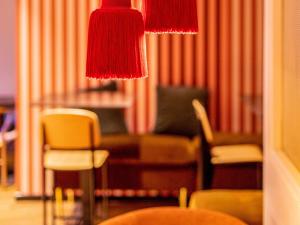 - un salon avec des chaises et une lampe rouge dans l'établissement Ibis Styles St Etienne - Gare Chateaucreux, à Saint-Étienne