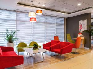 a waiting room with red chairs and a table at Ibis Izmir Alsancak in Izmir