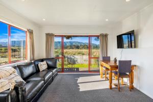 a living room with a black leather couch and a desk at Cottage on Rutherford - Waikanae Holiday Home in Waikanae