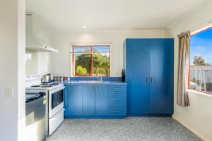 a blue kitchen with a sink and a window at Cottage on Rutherford - Waikanae Holiday Home in Waikanae