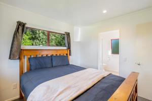 a bedroom with a bed with a wooden headboard and a window at Cottage on Rutherford - Waikanae Holiday Home in Waikanae