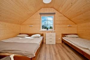 two beds in a wooden room with a window at Domki letniskowe Kajuta in Władysławowo