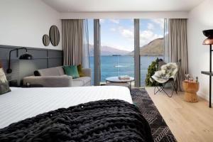 a bedroom with a bed and a view of the ocean at QT Queenstown in Queenstown