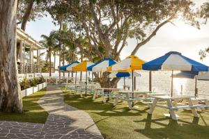 a row of tables with umbrellas on top of them at The Beachcomber Hotel & Resort, Ascend Hotel Collection in Toukley