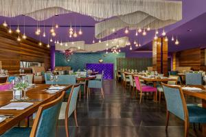 a restaurant with wooden tables and chairs and purple ceilings at Lazart Hotel, Trademark Collection by Wyndham in Thessaloniki