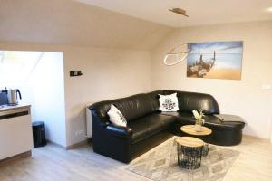 ein Wohnzimmer mit einem Ledersofa und einem Tisch in der Unterkunft Ferienwohnungen Zinnowitz in Zinnowitz
