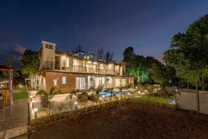 a large house with lights in the yard at night at SaffronStays Casa De Familia, Karjat - pool villa with ample open space for outdoor games in Jambrung 
