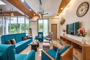 a living room with blue furniture and a large clock at SaffronStays Casa De Familia, Karjat - pool villa with ample open space for outdoor games in Jambrung 