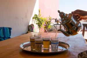 una persona vertiendo cerveza en vasos sobre una mesa en Azrac Surf Morocco, en Agadir