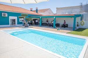 einem Pool vor einem Haus mit einem blauen Gebäude in der Unterkunft Delmira Vineyard House in Águas de Moura