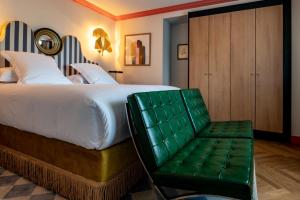 a bedroom with a large bed and a green chair at Château de Fiac - Luxurious Hôtel & Spa in Fiac