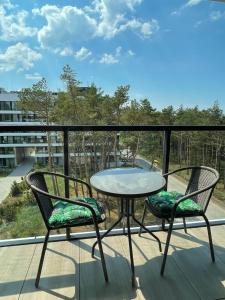 balcón con mesa de patio y 2 sillas en Apartament z widokiem na morze Shellter Rogowo en Rogowo
