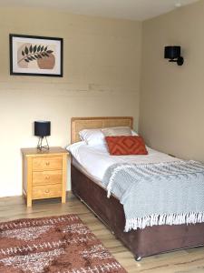 1 dormitorio con cama, mesita de noche de madera y cama sidx sidx sidx sidx en Kingfisher Barn B&B, en Abingdon