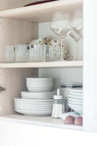 a white shelf with plates and bowls and dishes at Seagulls&Dunes APTw/terrace, 2min to the Beach, by Cohost in Klaipėda +36 photos