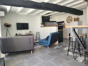 a living room with a blue chair and a television at Maison de campagne individuelle et patio in Poulan-Pouzols +5 photos