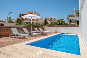 a swimming pool with chairs and an umbrella next to a house at Villa Ullastre in Manacor