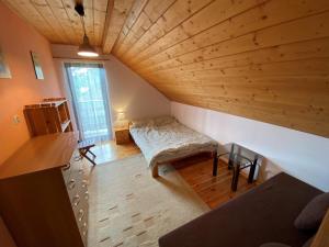 an attic room with a bed and a wooden ceiling at Dom w Puszczy Augustowskiej in Płaska