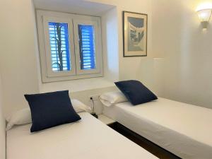 two beds in a room with two windows at PALAU - Gran casa de pueblo con fantásticas vistas al mar in Cadaqués