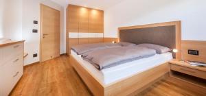 Schlafzimmer mit einem großen Bett mit einem Kopfteil aus Holz in der Unterkunft Avea App 1 in Lajen