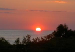 um pôr-do-sol sobre o oceano com o sol no céu em Il Varo a Mare em Punta Braccetto