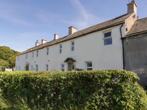 una casa blanca con un seto delante de ella en Fellside Cottage, en Cockermouth