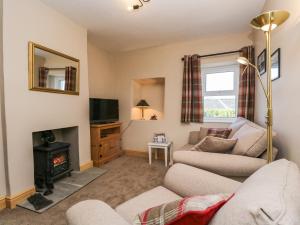 sala de estar con sofá y chimenea en Fellside Cottage, en Cockermouth