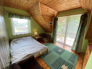 ein kleines Schlafzimmer mit einem Bett und einem großen Fenster in der Unterkunft Bociani Domek in Płaska