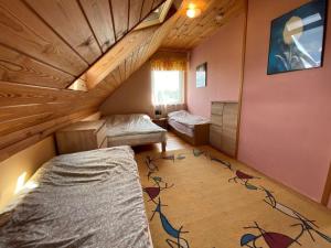 a room with two beds and a wooden ceiling at Bociani Domek in Płaska