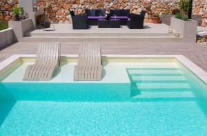 una piscina con 2 sillas junto a una mesa en Villa Green Pearl, en Gostinjac